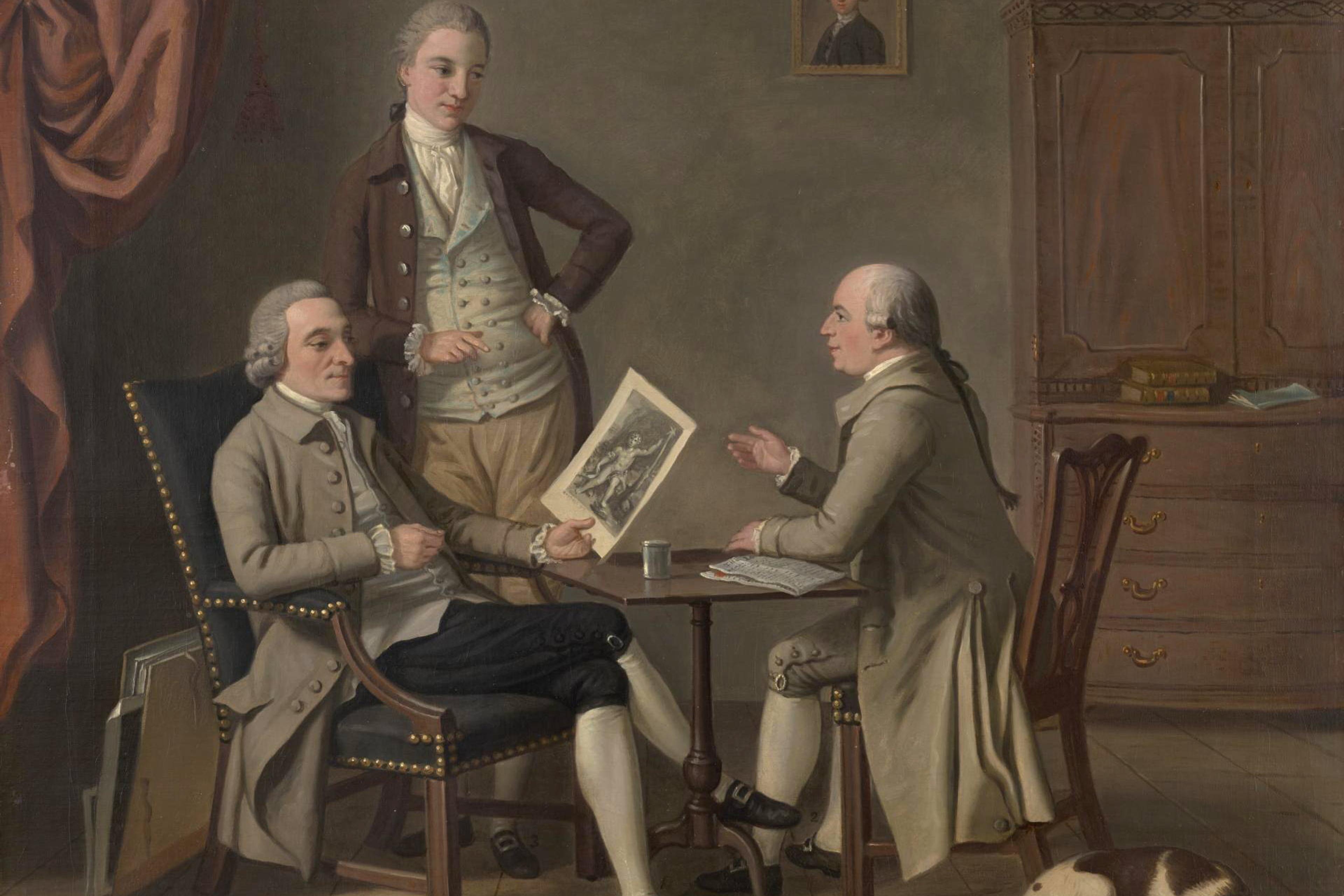 Painting of three 18th-century men in discussion, one holding an illustration. A dog lies on the floor.