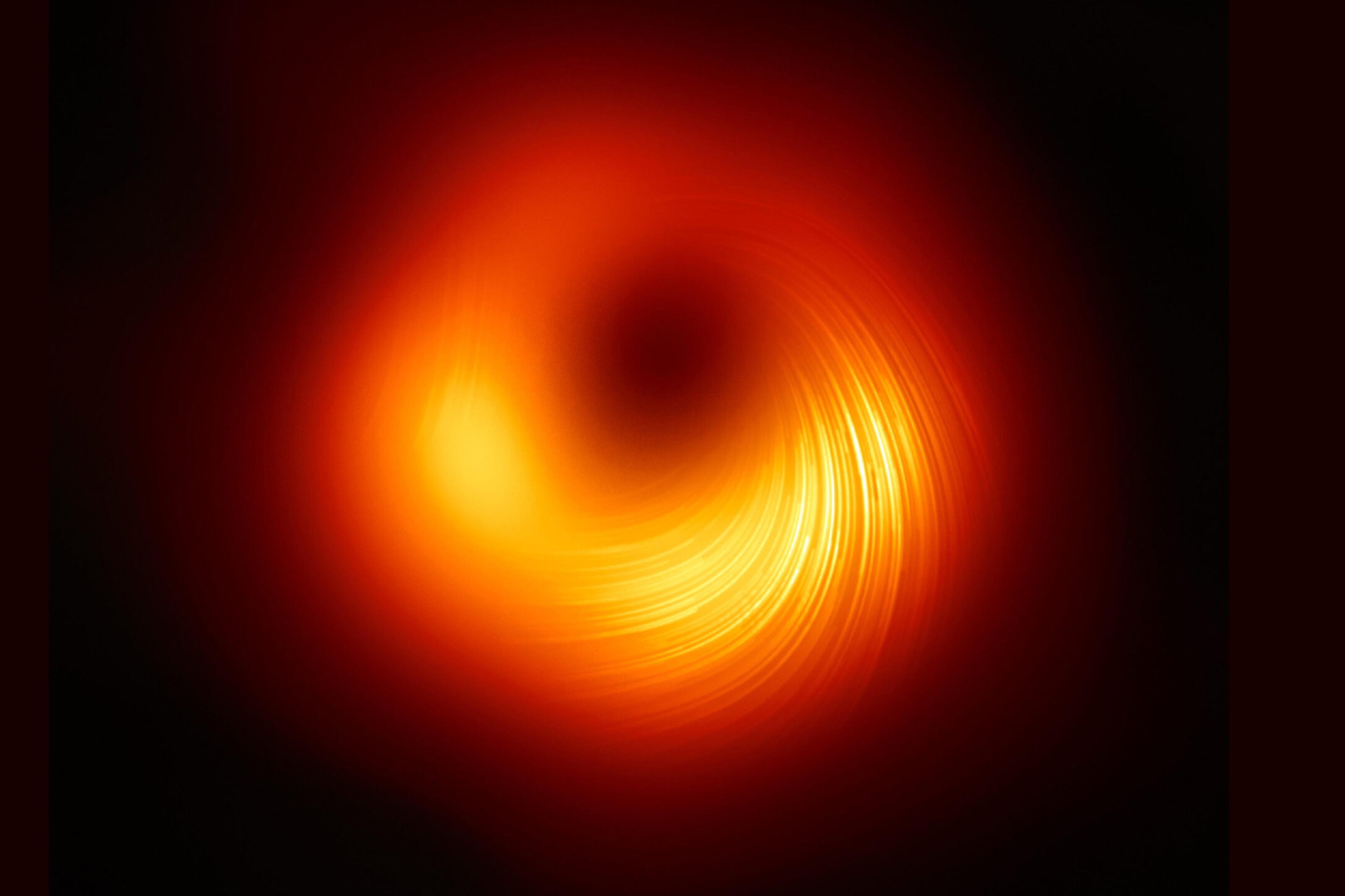 A black hole, showing a glowing orange-red ring surrounded by darkness, captured by a telescope.